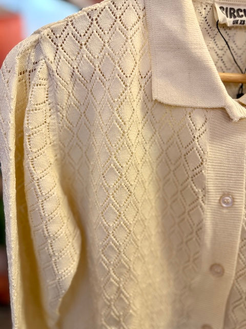 Detailaufnahme der cremefarbenen Circus Clothing Ajour Strickjacke mit filigranem Rautenmuster, Kragen und dekorativer Knopfleiste.