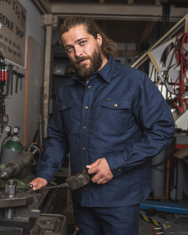 Mann trägt 1943 CPO Shirt Hamburg Blue von Pike Brothers in der Werkstatt