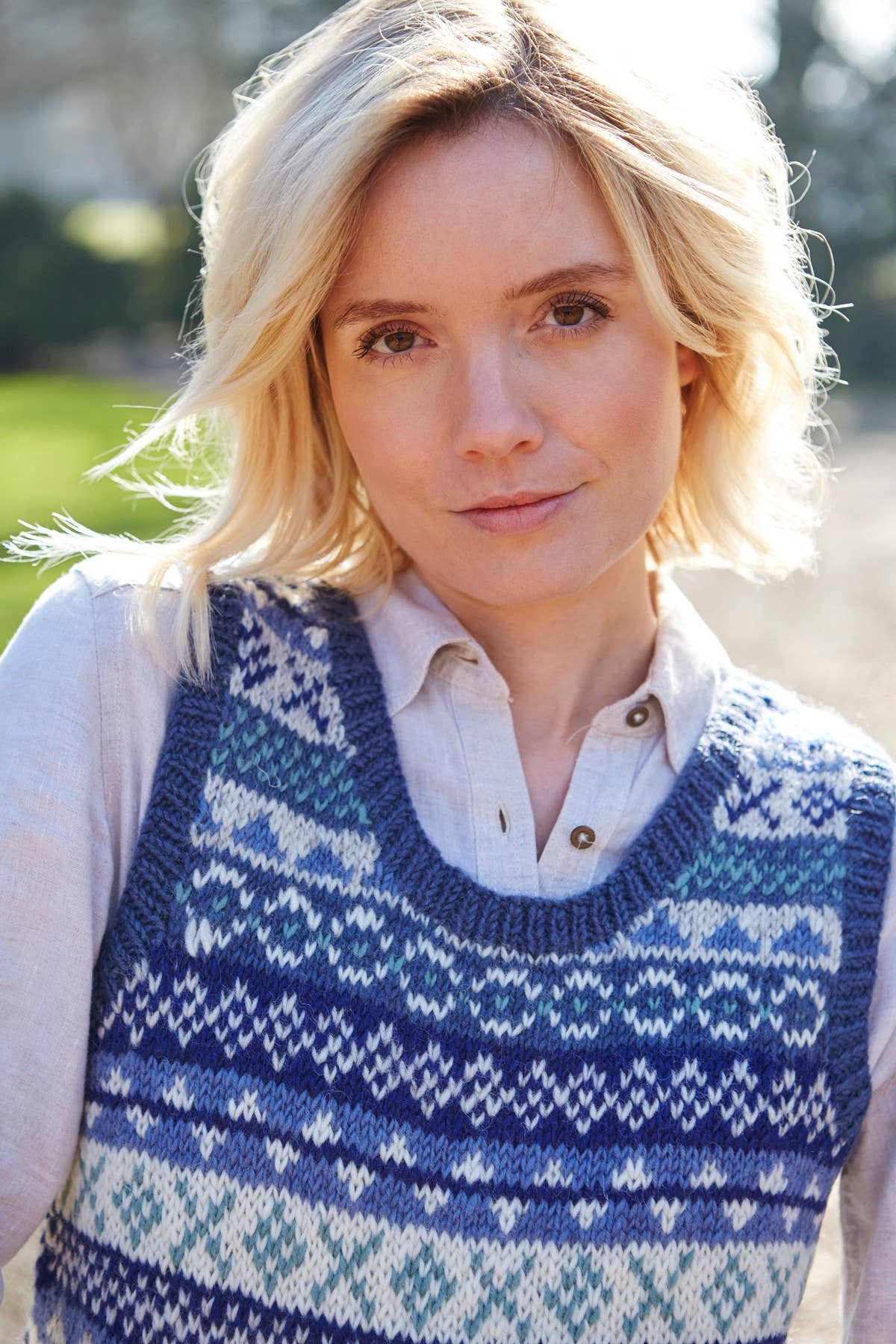 Frau trägt klassische Fair Isle Wollstrickweste in Blau mit traditionellem Muster – handgemacht aus 100 % Wolle