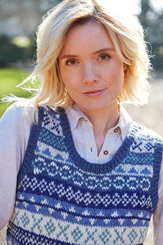 Frau trägt klassische Fair Isle Wollstrickweste in Blau mit traditionellem Muster – handgemacht aus 100 % Wolle